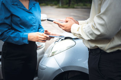 Midsection of woman holding umbrella while standing by car