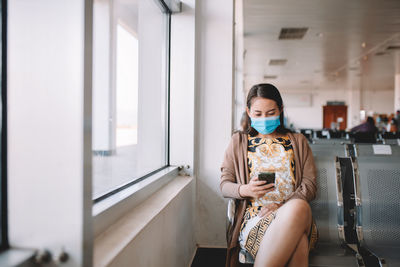 Full length of young woman using mobile phone