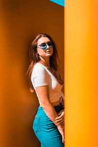 Woman wearing sunglasses standing against wall