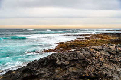 Scenic view of rocks on beach against sky
