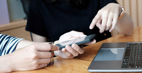 Midsection of woman using smart phone on table