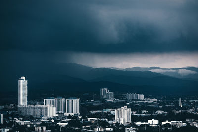 Buildings in city against storm clouds