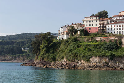 Buildings by sea against clear sky