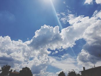 Low angle view of sunlight streaming through clouds