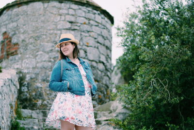 Portrait of smiling young woman standing against plants