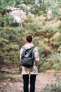 Rear view of woman standing in forest