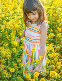 Young woman standing amidst yellow flowers