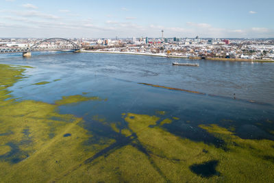 High angle view of city by sea against sky