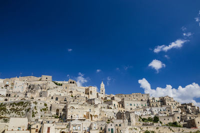 Low angle view of old buildings in town against blue sky