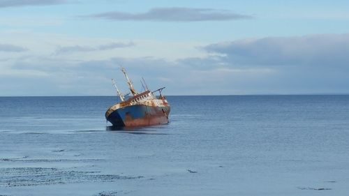 Boats in sea against cloudy sky