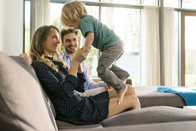 Happy parents playing with son on sofa at home