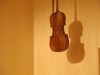 Violin hanging on yellow wall