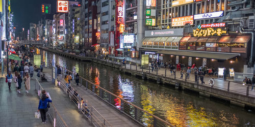 People walking on illuminated street in city at night