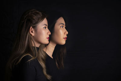 Young woman looking away against black background