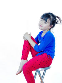 Girl looking away while sitting against white background