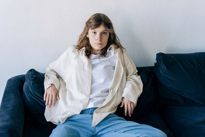 Portrait of young woman sitting on sofa at home