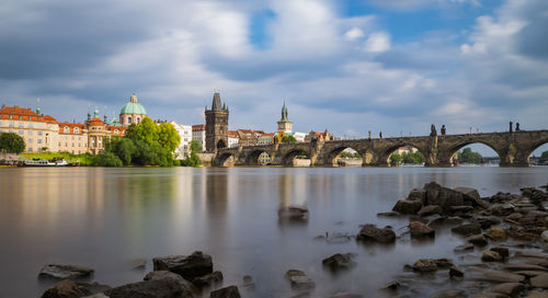 Arch bridge over river against buildings in city