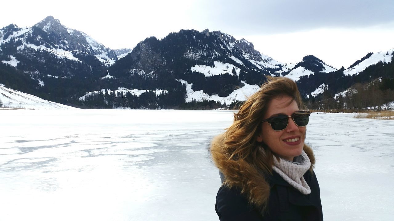 WOMAN STANDING ON SNOW COVERED MOUNTAINS