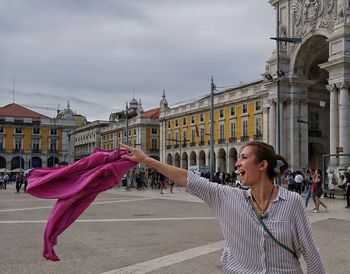 Woman standing by building in city against sky