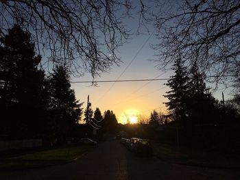 Road amidst trees against sky during sunset