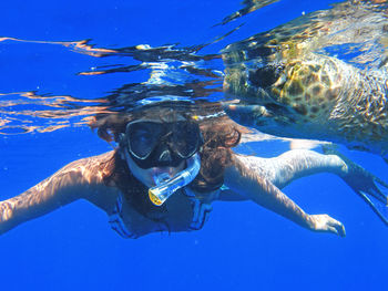 Young woman swimming by turtle in sea