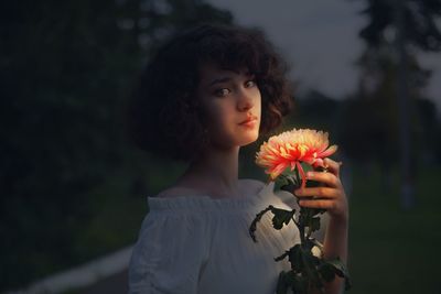 Portrait of woman holding red flower