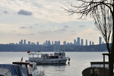 Boats in sea by buildings against sky in city