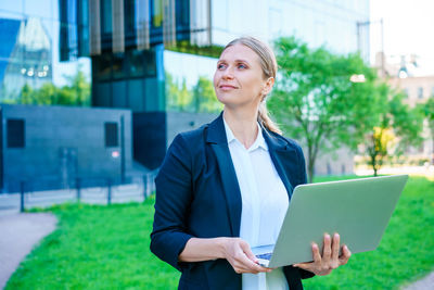 Portrait young business woman with smile with laptop in her hands stands