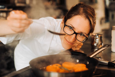 Female chef is checking cooked apricot confiture