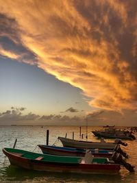 Boats moored on sea against sky during sunset