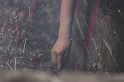 Cropped hand of woman placing lit incense stick in ash
