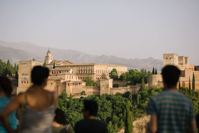 Rear view of people looking at buildings against sky