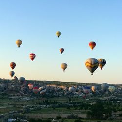 Hot air balloons flying over landscape against clear sky