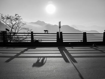 Shadow of railing on mountain against sky
