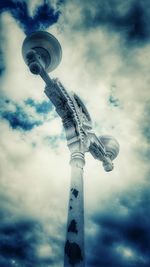 Low angle view of communications tower against cloudy sky