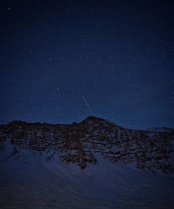 Scenic view of snowcapped mountains against star field at night