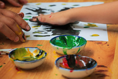 Cropped hands of people painting on paper over table