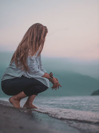 Rear view of woman at beach during sunset