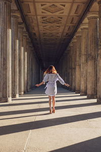 Rear view of young woman standing amidst columns