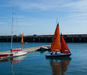 Sailboats moored on sea against sky