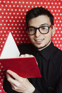 Smiling man wearing eyeglasses while reading book