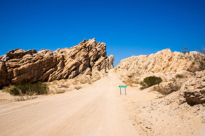 Road amidst desert against clear blue sky