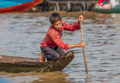 Full length of man holding boat in lake