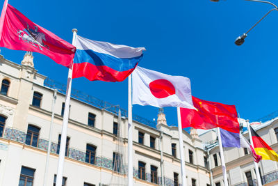 Low angle view of various flags against clear blue sky
