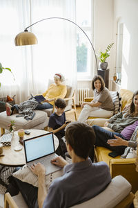 Multi-generation family talking to each other while sitting in living room at home