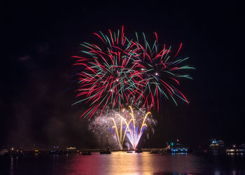 Low angle view of firework display over river at night
