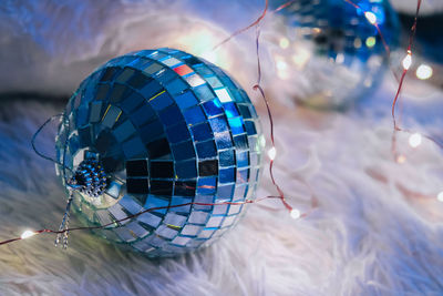 Two disco balls lying down on cozy blanket with christmas garland light. cozy home interior. home 