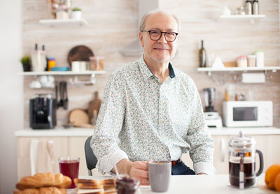 Portrait of smiling man holding coffee cup at home
