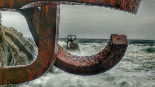 Old rusty ship at sea shore against sky