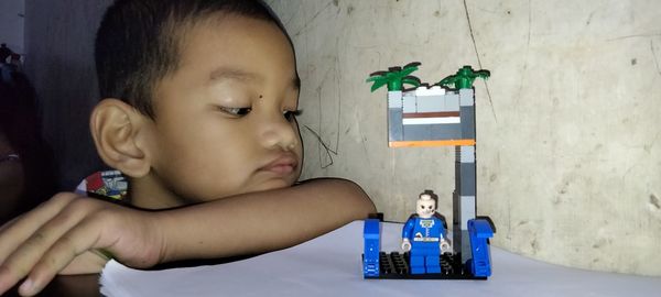 Portrait of cute boy with toy against wall at home